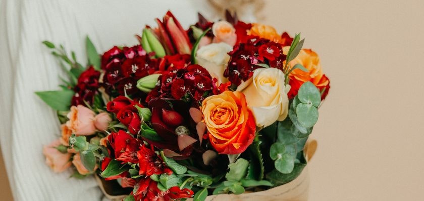 Vibrant bouquet featuring orange and red roses alongside assorted colorful blooms.