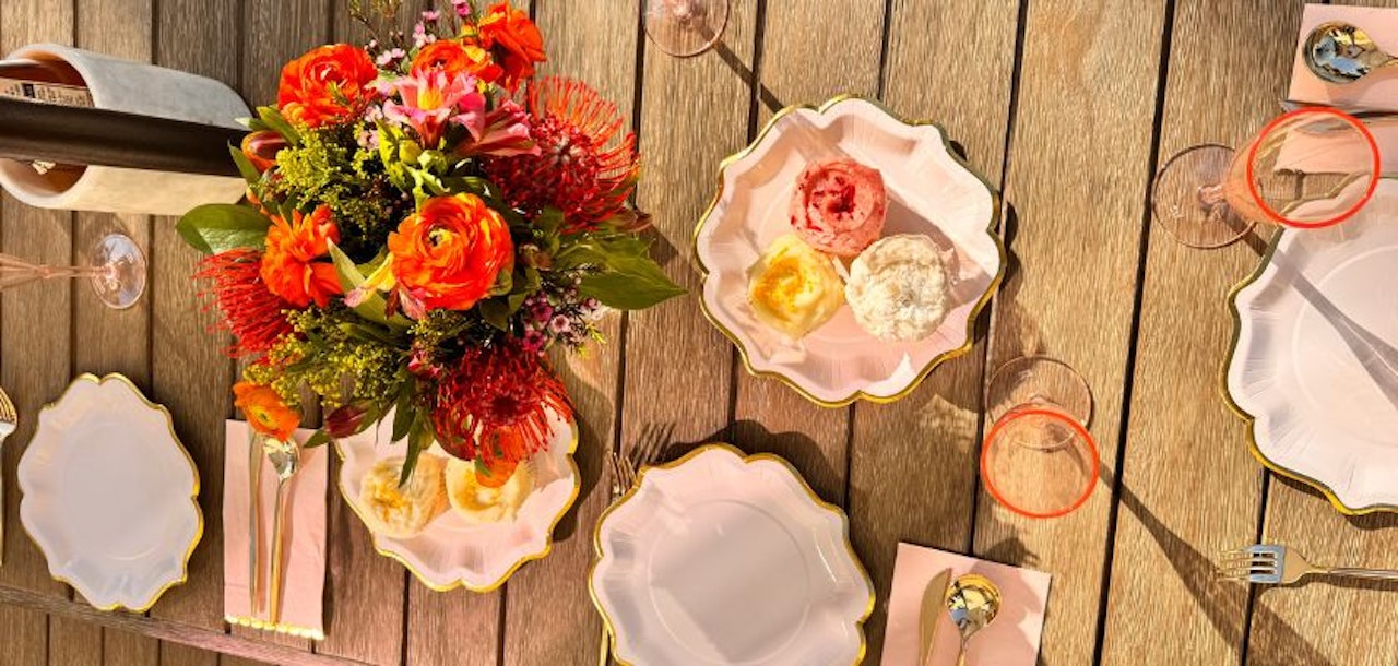Vibrant floral centerpiece with colorful blooms, set atop a stylish outdoor dining table.