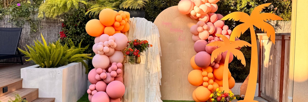 A vibrant tropical balloon arch with flowers, perfect for festive celebrations.