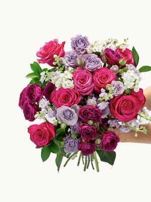 Vibrant bouquet featuring pink and purple roses, complemented by delicate white blooms.