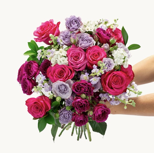 Vibrant bouquet featuring pink and purple roses, complemented by delicate white blooms.