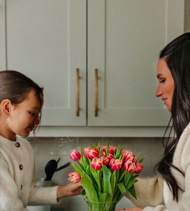 A mother and daughter share a joyful moment with a vibrant bouquet of tulips.