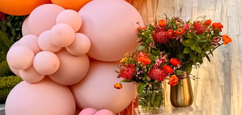 Colorful balloons and a vibrant floral arrangement enhance the festive atmosphere.