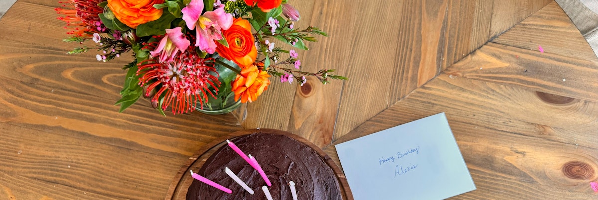 A festive birthday scene featuring a colorful floral bouquet and chocolate cake.