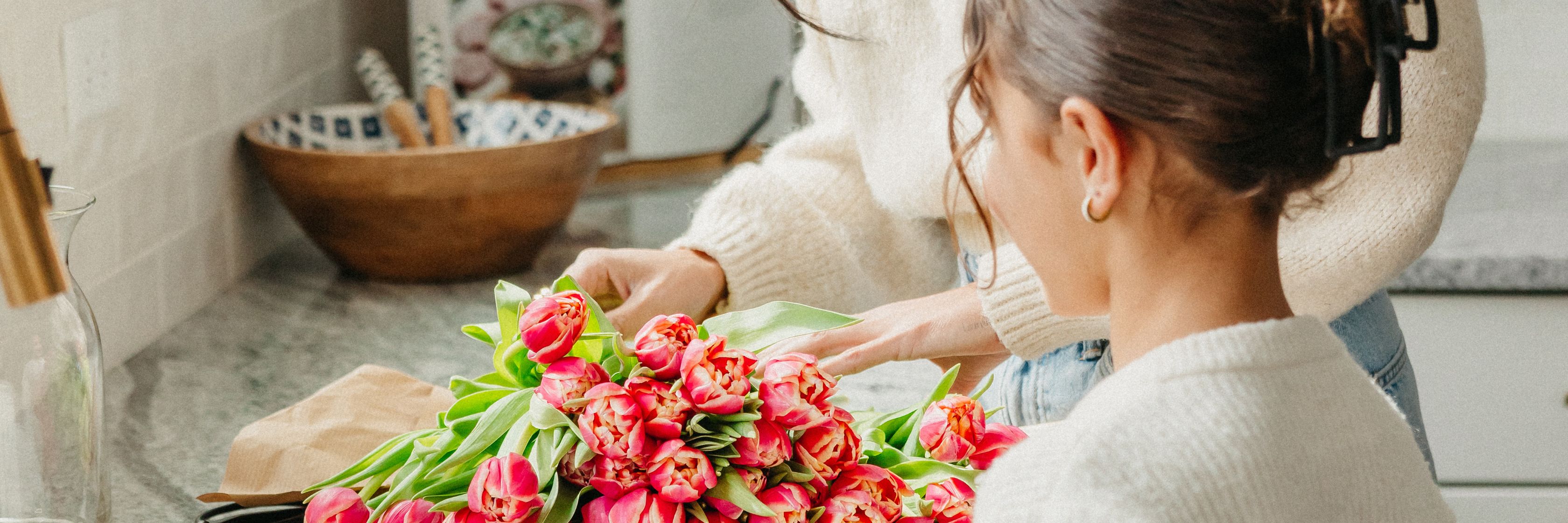 A woman carefully arranging a vibrant bouquet of pink tulips, showcasing floral artistry.