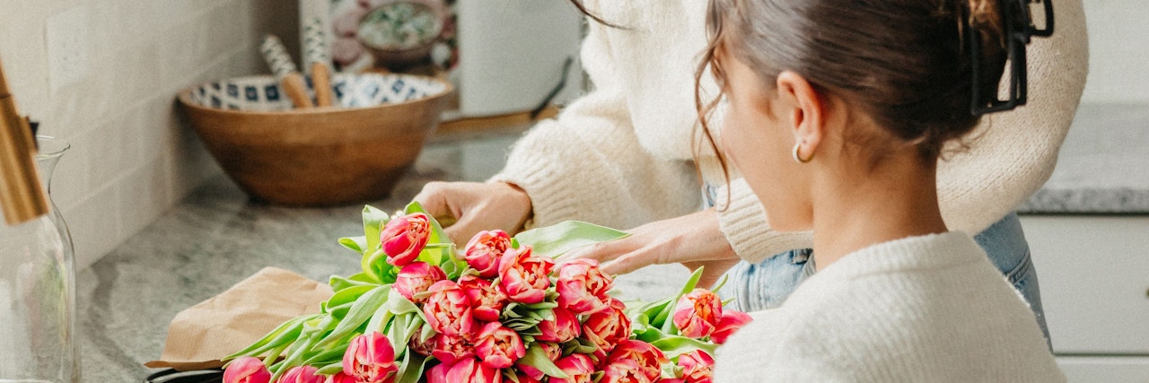 A woman carefully arranging a vibrant bouquet of pink tulips, showcasing floral artistry.