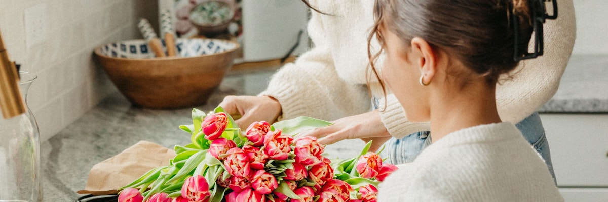 A woman carefully arranging a vibrant bouquet of pink tulips, showcasing floral artistry.