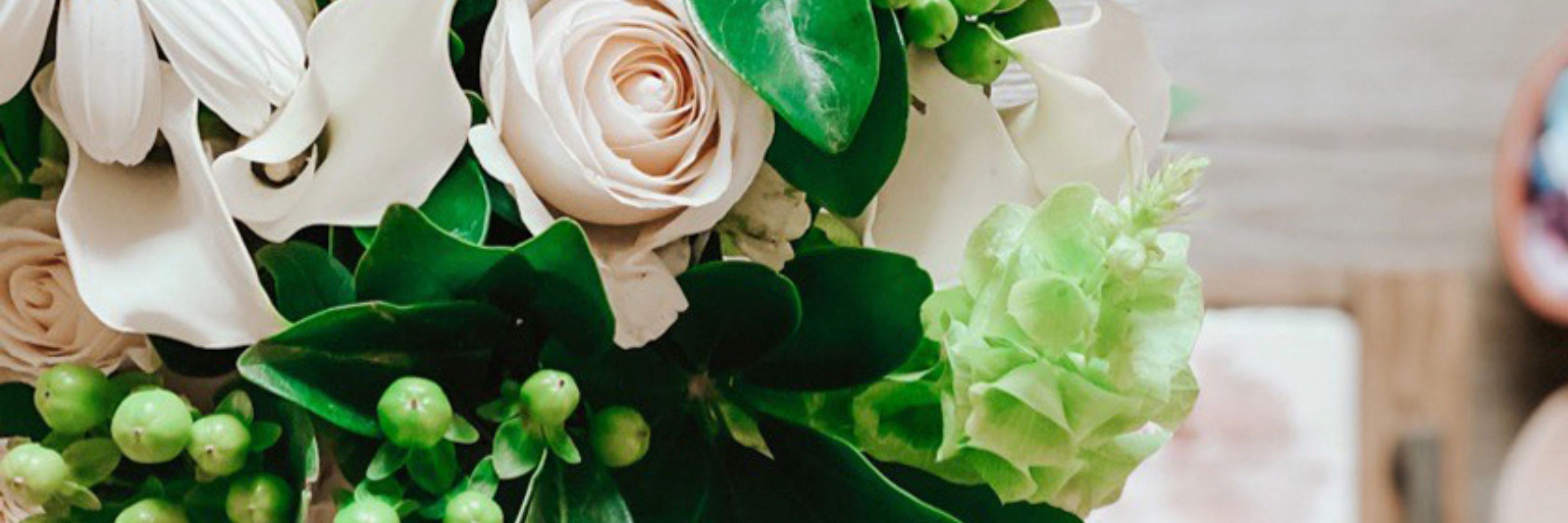 Elegant floral arrangement featuring blush roses, white blooms, and lush green accents.