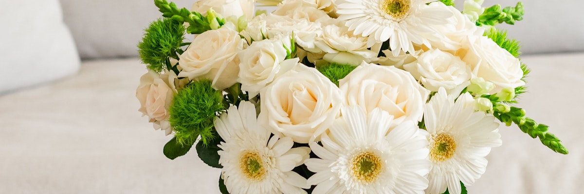 Elegant floral arrangement featuring white roses and daisies with green accents.