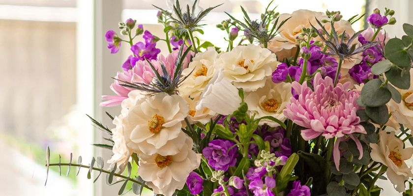 A vibrant floral arrangement featuring shades of purple and soft pink blooms, perfect for any occasion.