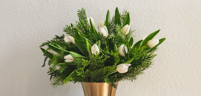 Elegant white tulips and lush greenery arranged in a chic gold vase, perfect for any decor.