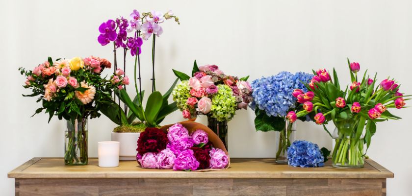 A vibrant floral display featuring lush roses, orchids, and tulips in elegant vases.