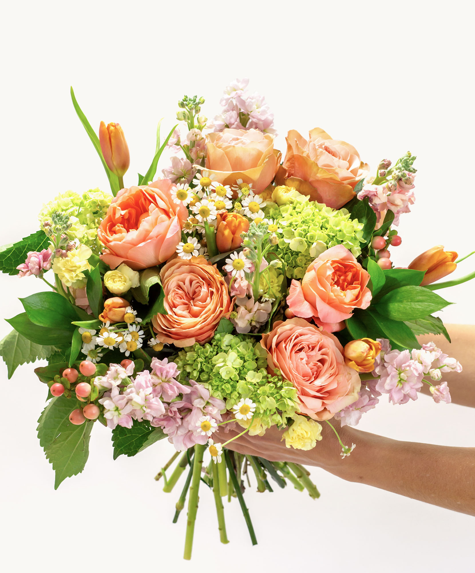 Vibrant floral bouquet featuring peach roses, green blooms, and delicate blossoms, elegantly arranged.