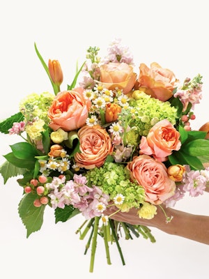 Vibrant floral bouquet featuring peach roses, green blooms, and delicate blossoms, elegantly arranged.