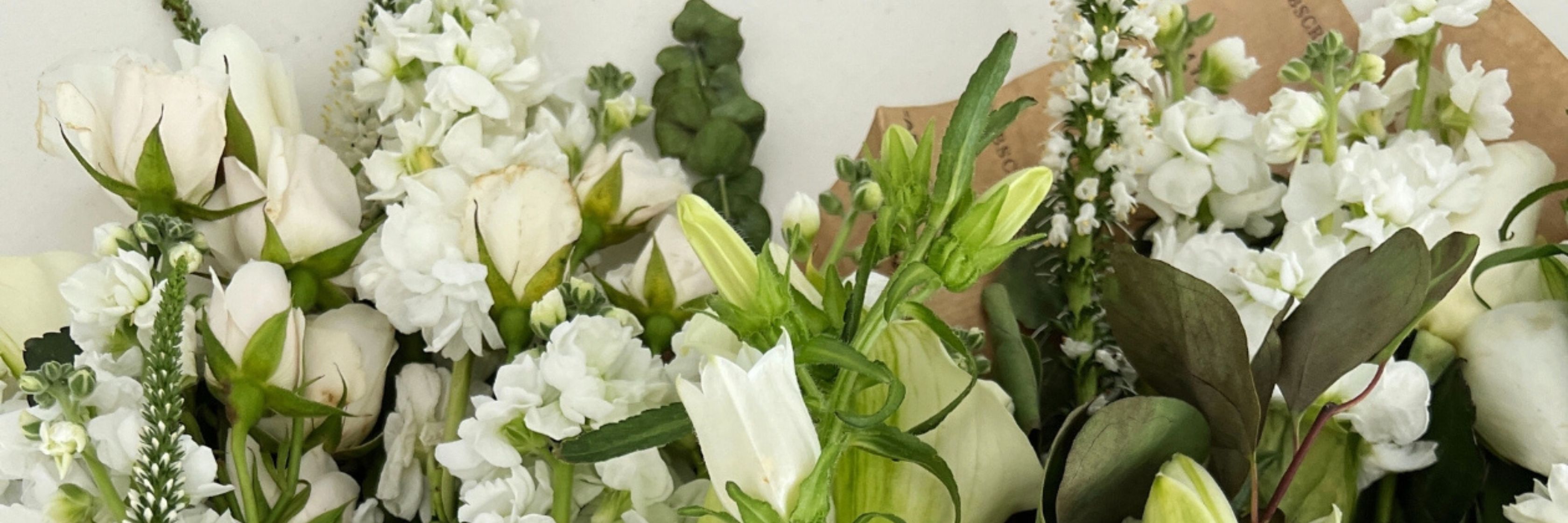 Elegant white floral arrangement featuring roses, snapdragons, and lush greenery.
