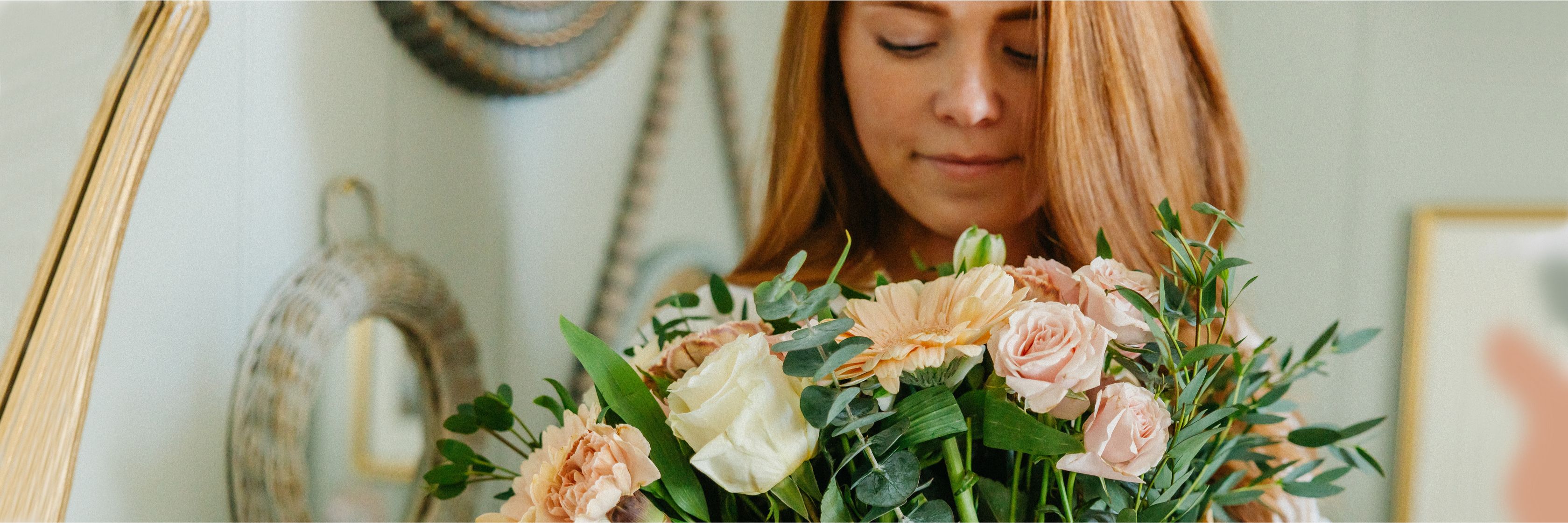 A woman holds a lush bouquet of pastel flowers, surrounded by elegant decor elements.