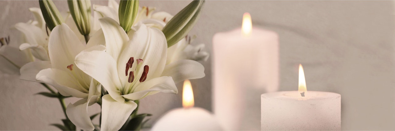 Elegant white lilies paired with softly glowing candles create a serene ambiance.