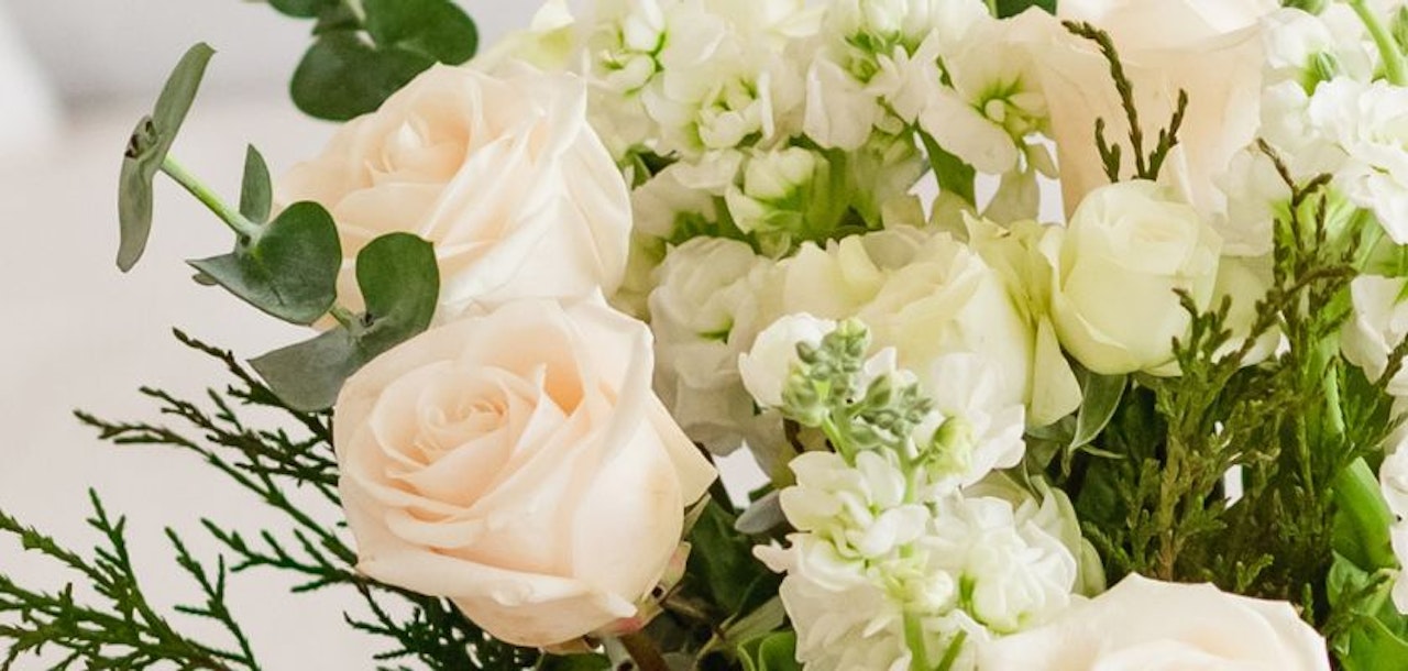 Elegant bouquet featuring soft pink roses and white blooms with lush greenery accents.