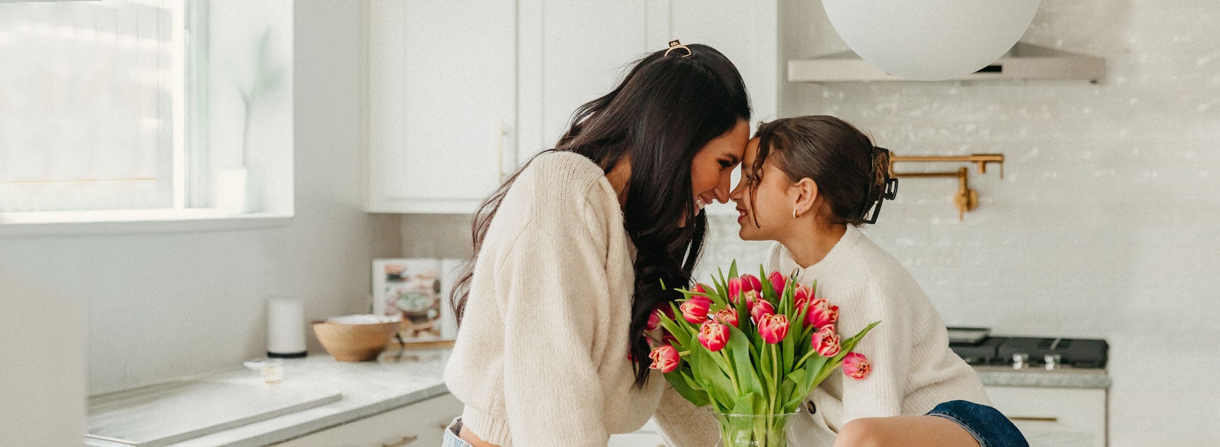 A joyful moment between two people sharing a vibrant bouquet of tulips in a kitchen.