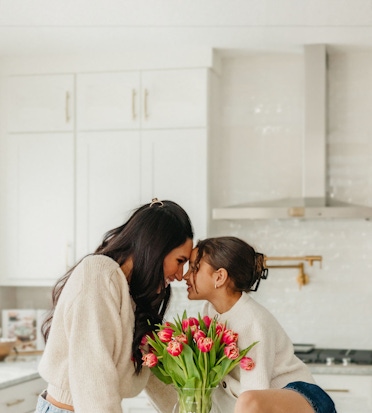A joyful moment between two friends sharing laughter over a vase of vibrant tulips.
