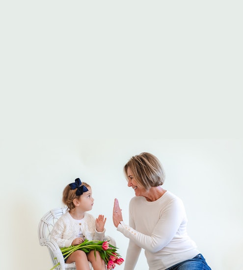 A joyful moment between a grandmother and granddaughter with tulips, sharing laughter together.