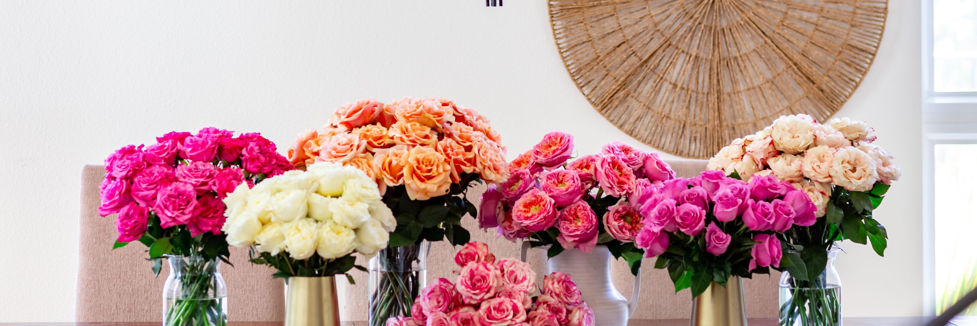 Vibrant floral display featuring pink, peach, and white roses in elegant vases.