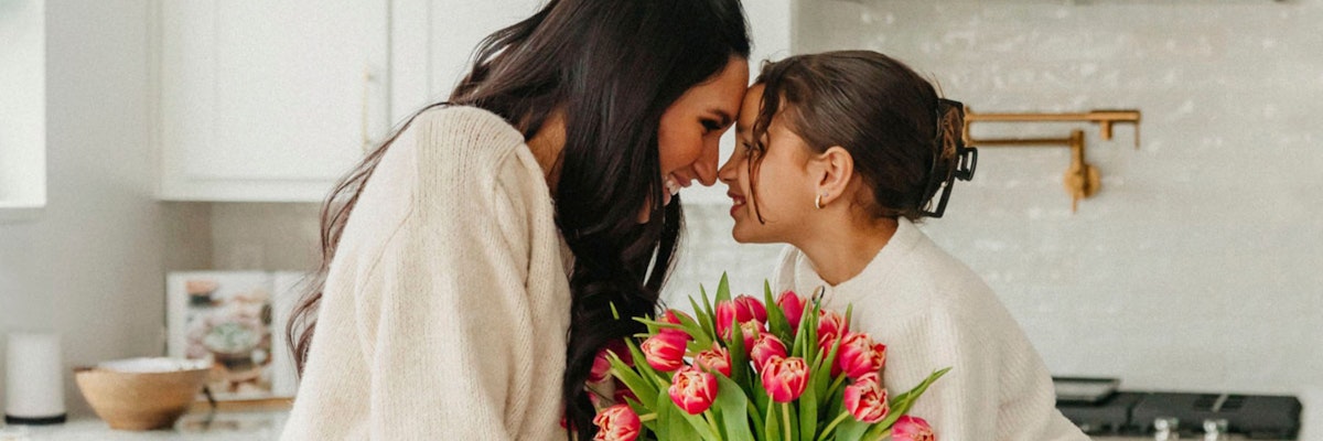 A joyful moment shared between a mother and daughter with a vibrant bouquet of tulips.