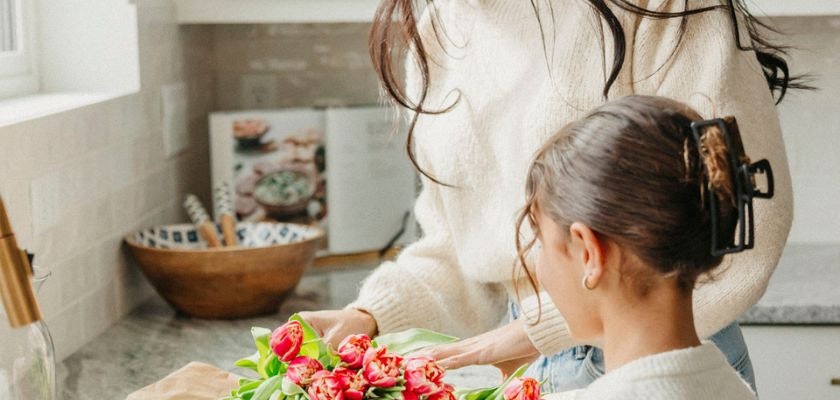 A woman and child joyfully arranging vibrant tulips in a cozy kitchen setting.