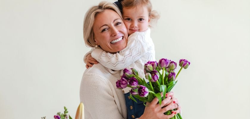 A joyful moment between a mother and daughter, holding a vibrant bouquet of tulips.