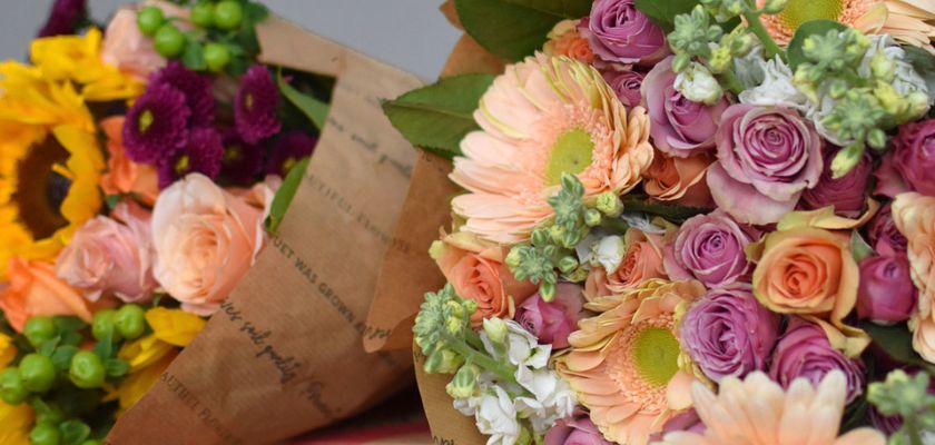 Colorful bouquet featuring vibrant sunflowers, roses, and delicate daisies in a chic arrangement.
