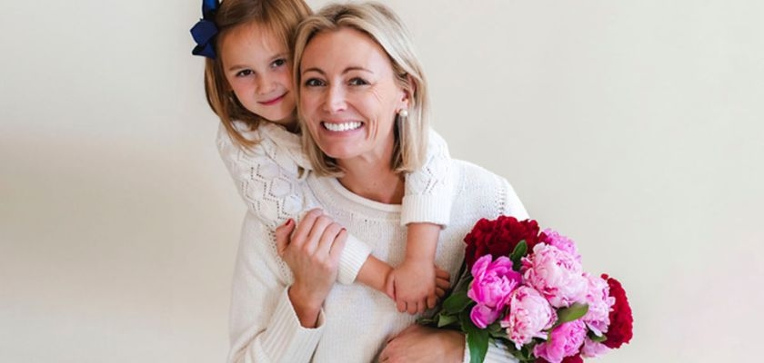 A smiling mother and daughter holding a beautiful bouquet of pink peonies and roses.