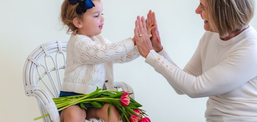 A joyful moment between a grandmother and granddaughter, sharing a playful interaction.
