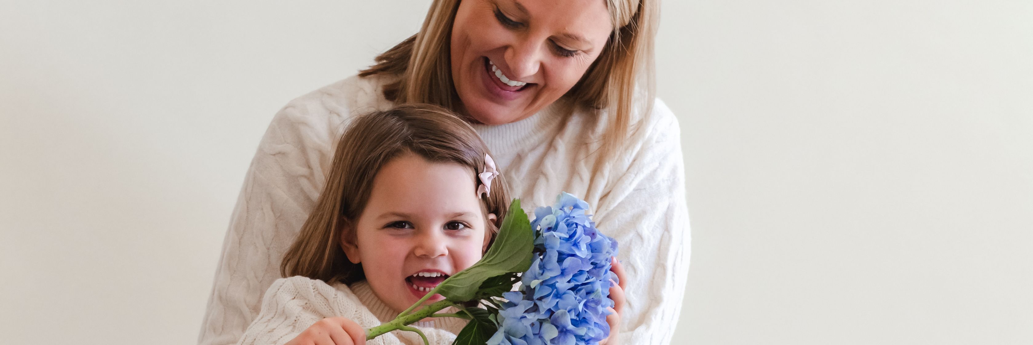 A joyful moment between a mother and daughter, sharing blue flowers together.