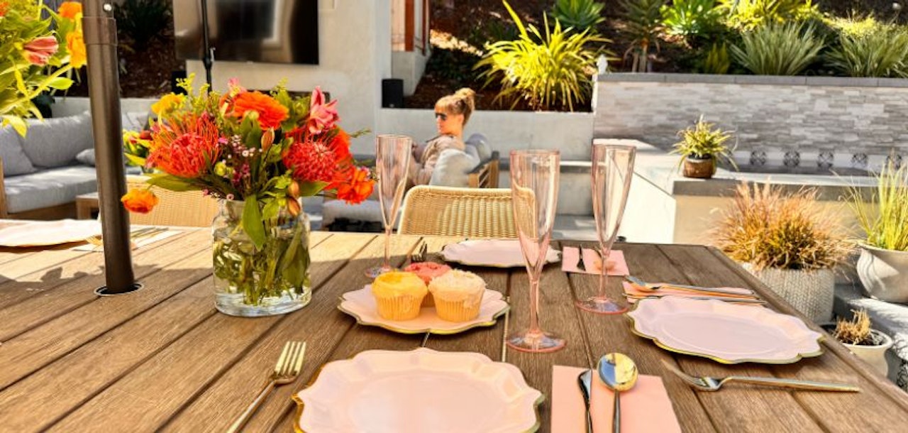 A beautifully set outdoor dining table with floral centerpiece and elegant tableware.