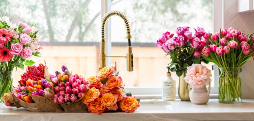 A vibrant display of fresh flowers in vases, showcasing colorful blooms in a sunny kitchen.