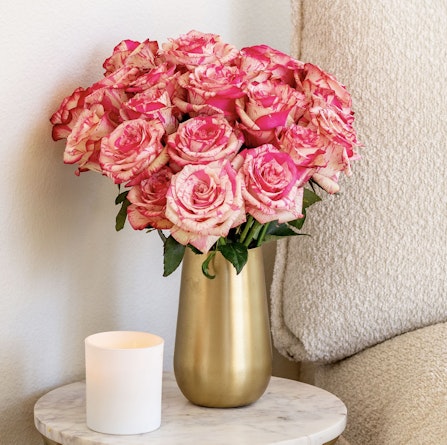 A vibrant bouquet of pink and cream roses in a chic gold vase, enhancing home decor.