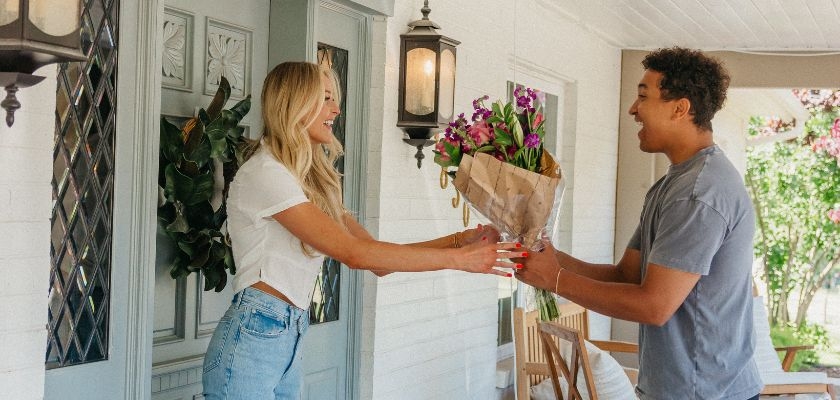 A joyful delivery moment featuring a couple exchanging a beautiful floral bouquet.