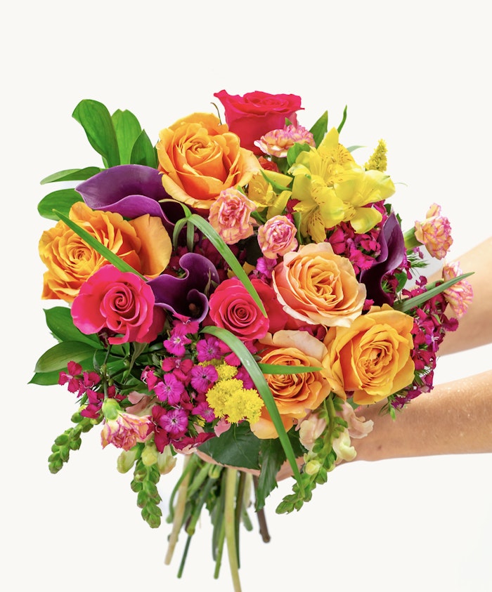 Vibrant bouquet featuring orange roses, purple blooms, and lush greenery, ideal for celebrations.