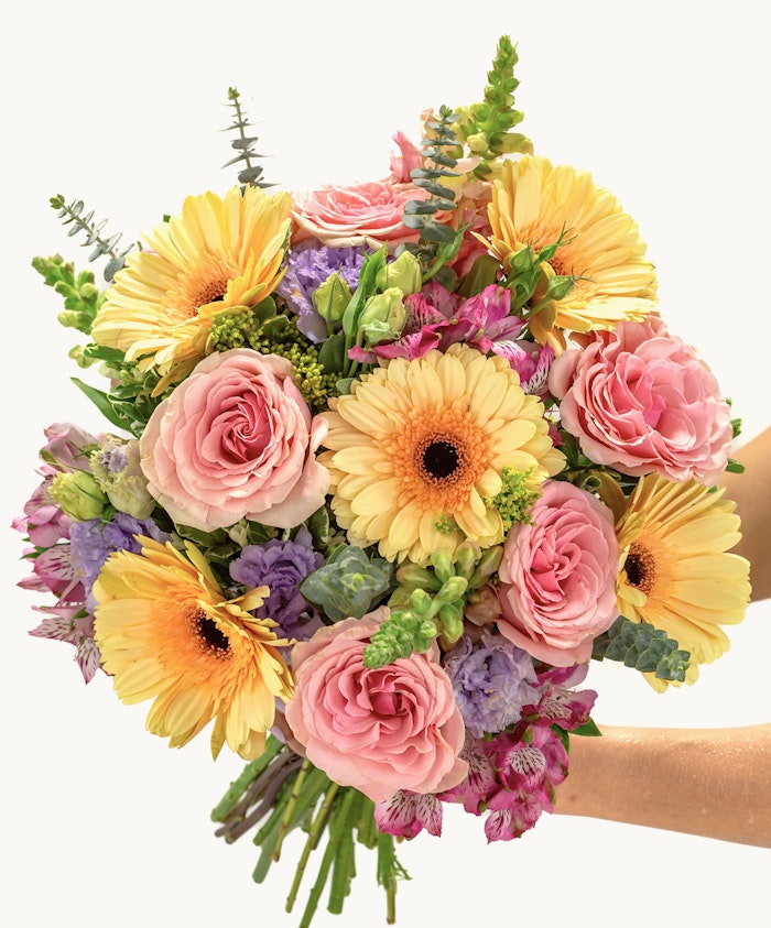Bright and cheerful bouquet of yellow gerberas, pink roses, and lush greenery.