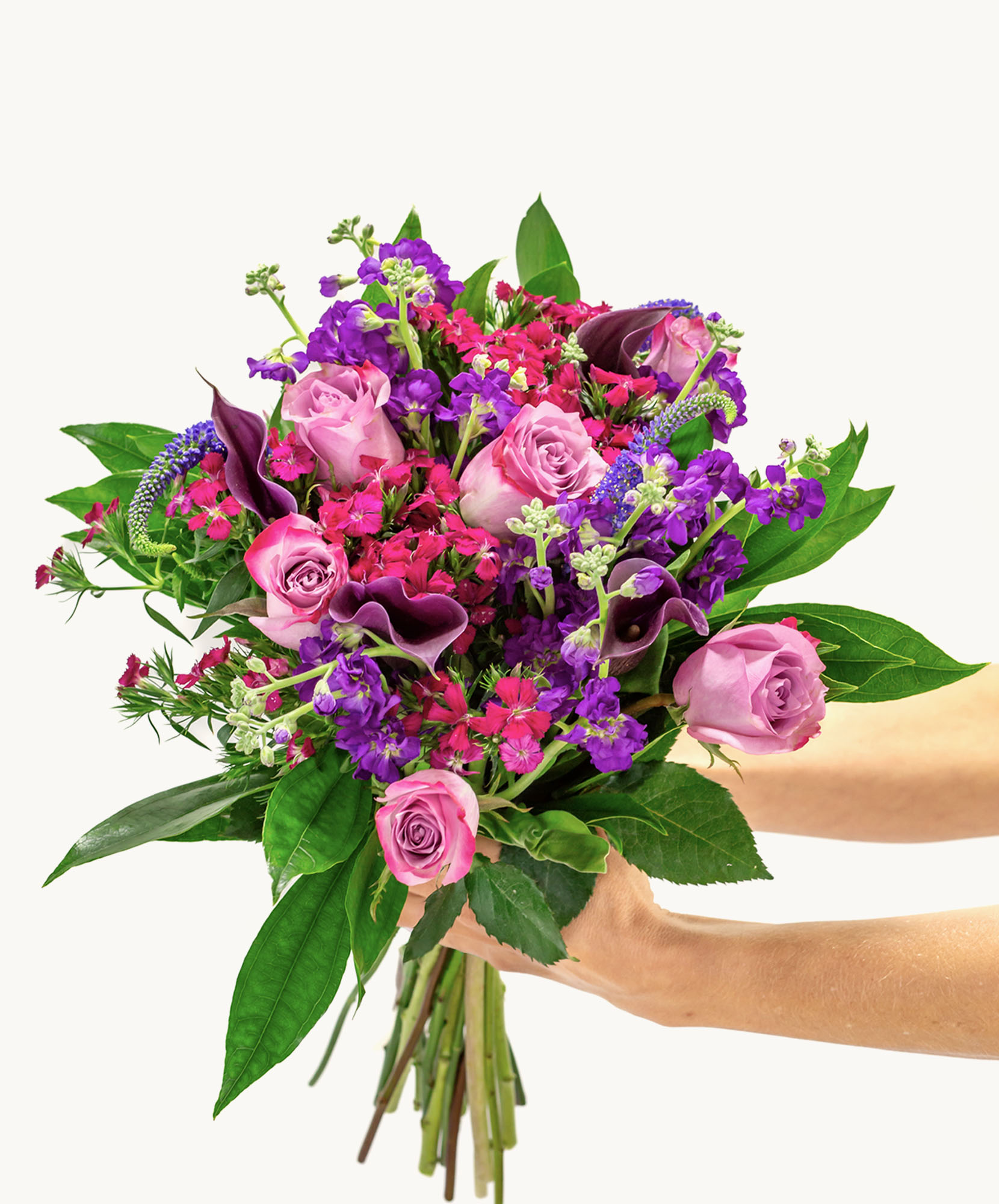 Vibrant bouquet featuring pink roses, purple blooms, and lush greenery, elegantly arranged.