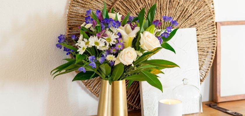 Vibrant floral arrangement featuring white roses, purple blooms, and greenery in a vase.