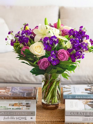 Vibrant mixed flower bouquet featuring purple, pink, and white blooms in a glass vase.