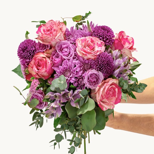 Vibrant bouquet of pink and purple roses, chrysanthemums, and greenery for special occasions.