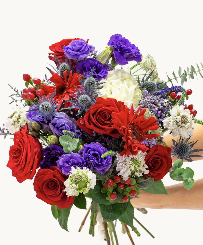Vibrant bouquet featuring red roses, purple blooms, and lush greenery for special occasions.