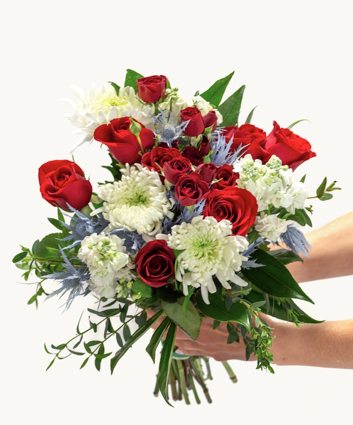 Vibrant bouquet featuring red roses, white daisies, and greenery, perfect for celebrations.