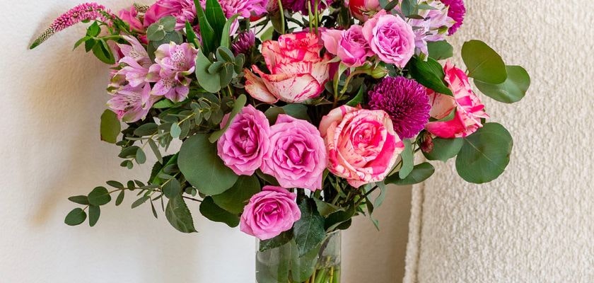 Vibrant floral arrangement featuring pink roses and alstroemeria in a glass vase.