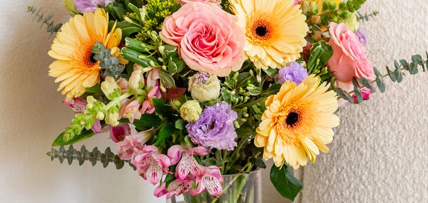 Vibrant floral arrangement featuring pink roses, gerbera daisies, and purple blooms.