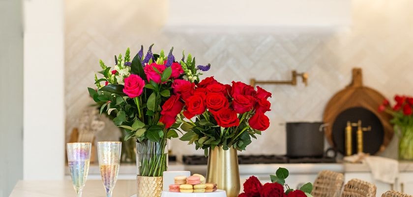 Vibrant red roses and colorful macarons in a stylish kitchen setting for celebrations.