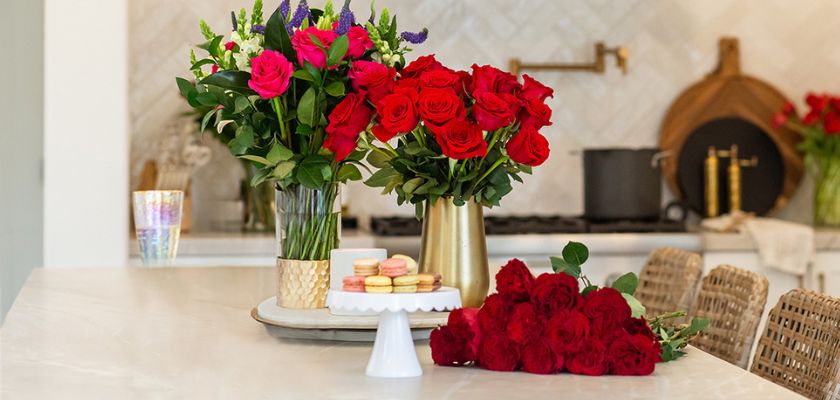 Vibrant red rose bouquets and colorful macarons on a stylish kitchen countertop.