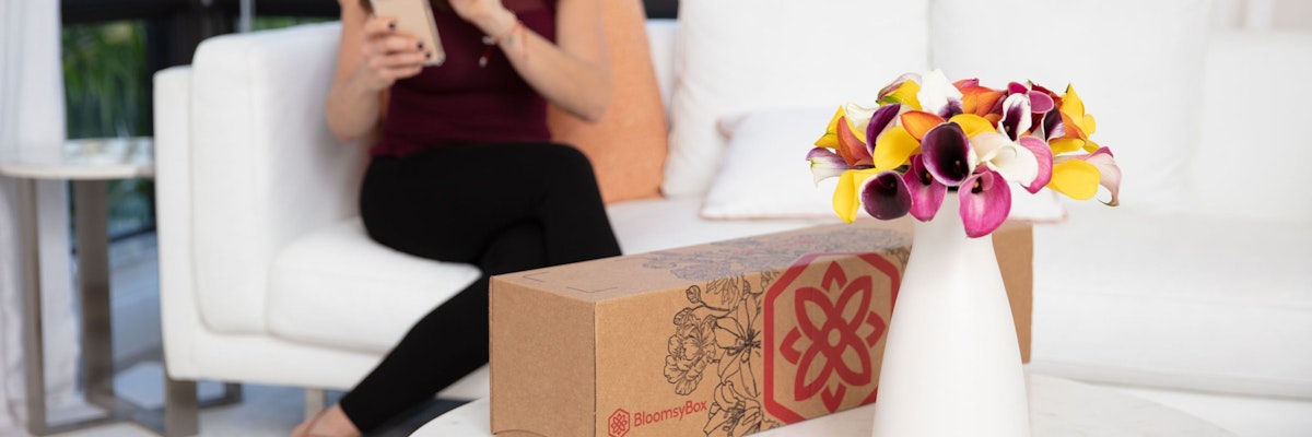A vibrant bouquet of colorful calla lilies placed beside a BloomsyBox delivery.